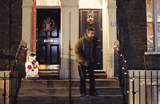 a man is standing in front of a house with the number 21 on the front door