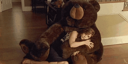 a woman laying on the floor hugging a giant teddy bear