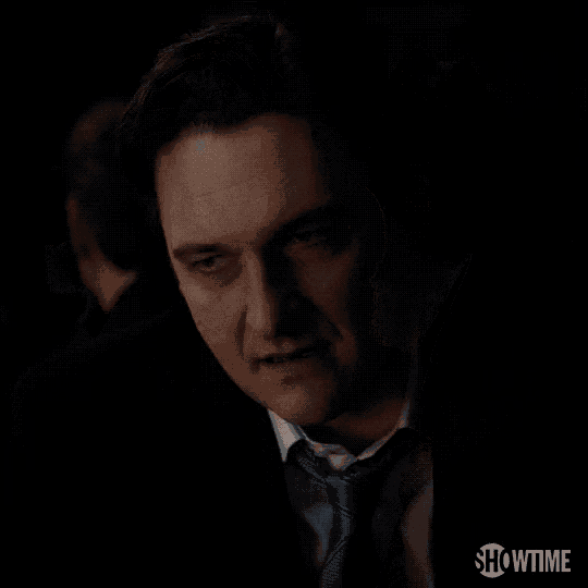a man in a suit and tie is standing in a dark room .