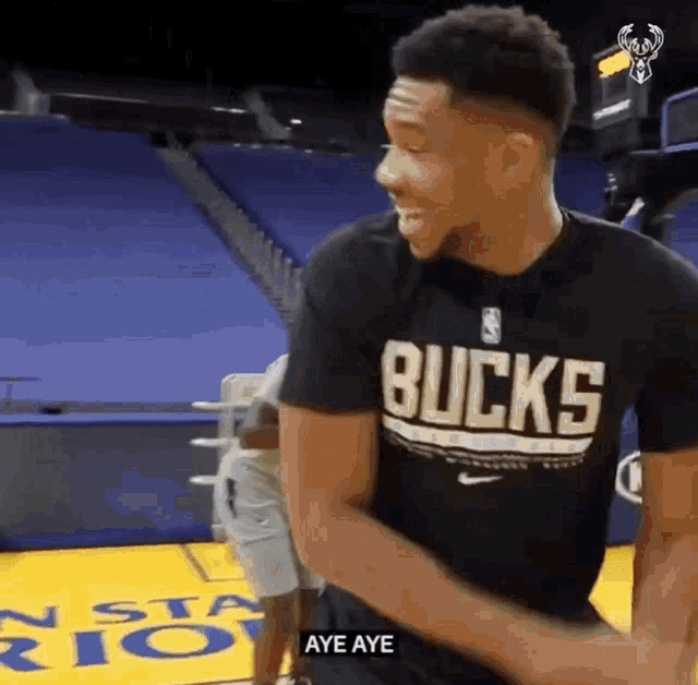 a basketball player wearing a black shirt with the word bucks on it is standing on a basketball court .