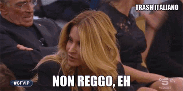 a woman in a black dress is sitting in front of a group of people and says non reggo eh