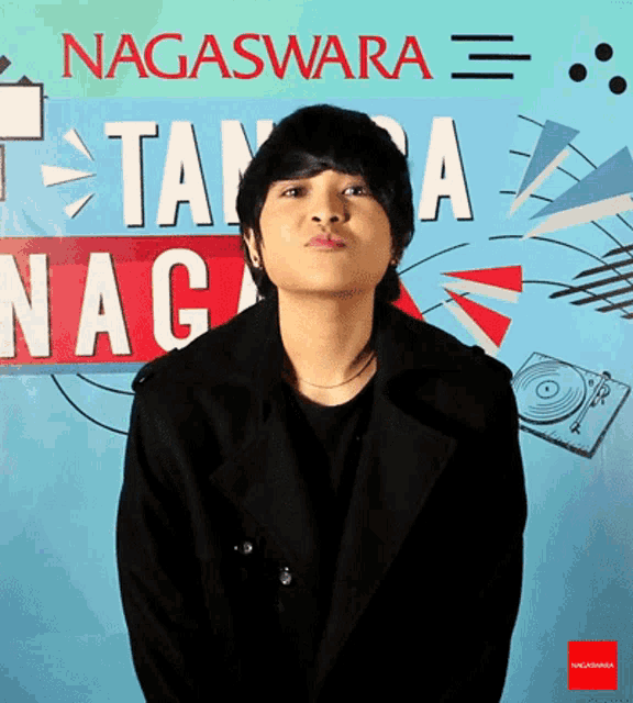 a young man stands in front of a sign that says nagasawara
