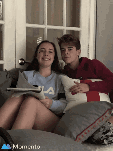 a girl wearing a fila sweater sits next to a boy