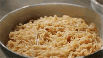 a bowl of noodles is being cooked in a pan on a table .