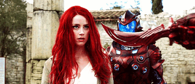 a woman with red hair is standing next to a robot