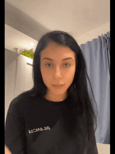 a woman wearing a black t-shirt with the letters ai on it looks at the camera