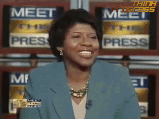 a woman in a blue jacket is smiling in front of a wall that says meet the press