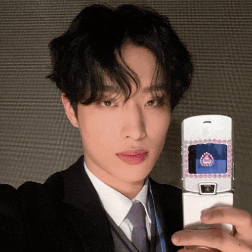 a man in a suit is taking a selfie with a flip phone