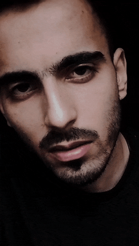 a close up of a man 's face with a black shirt on