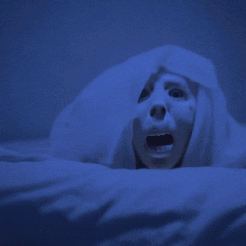a person with their mouth open is laying under a blanket