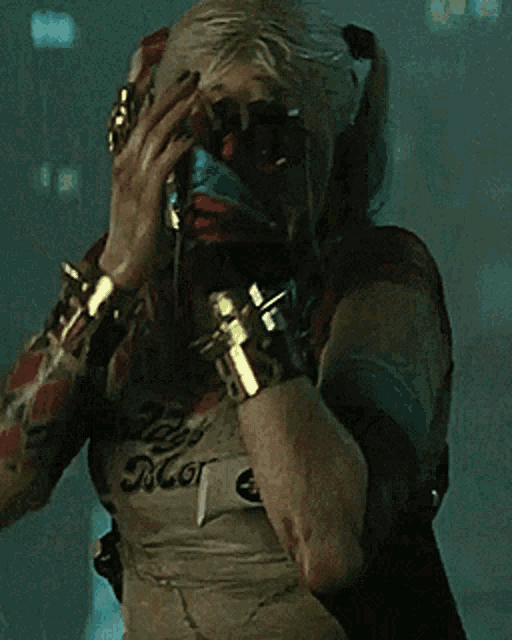 a woman in a suicide squad costume covering her face with her hands .
