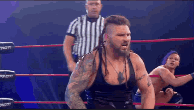a man in a black tank top is in a wrestling ring