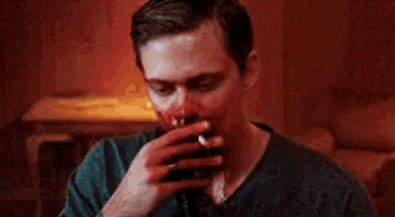 a man with blood on his face smoking a cigarette .
