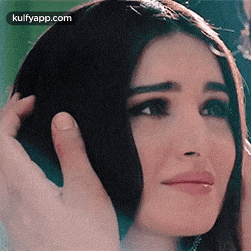 a close up of a woman holding her hair with her hands .