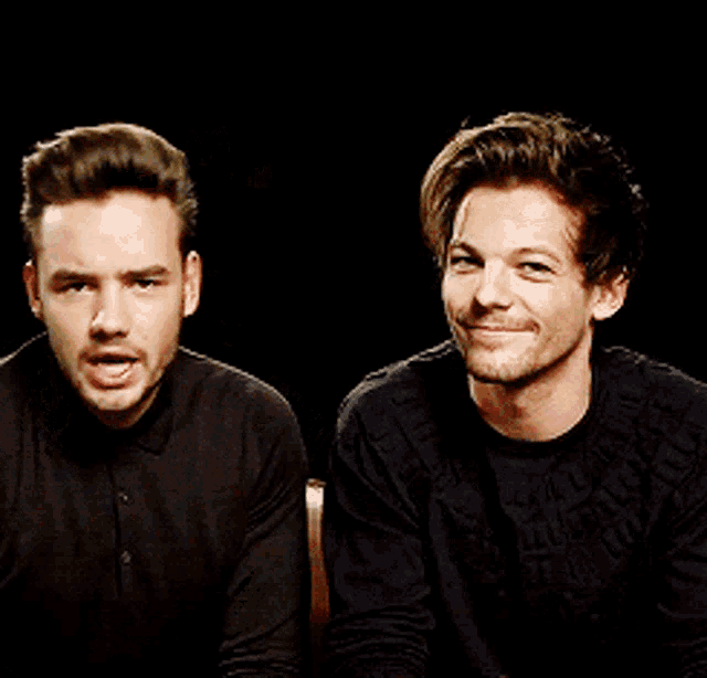 two men are sitting next to each other and one of them is wearing a black sweater with the word louis on it