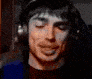 a man wearing headphones is smiling with his eyes closed and his mouth open .