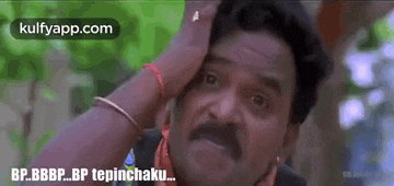 a man with a mustache is scratching his head with his hand .