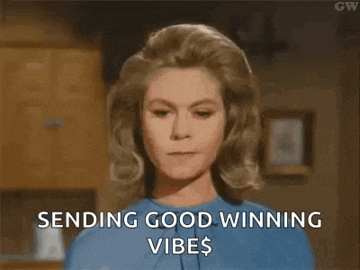 a woman in a blue shirt is sending good winning vibes to someone .