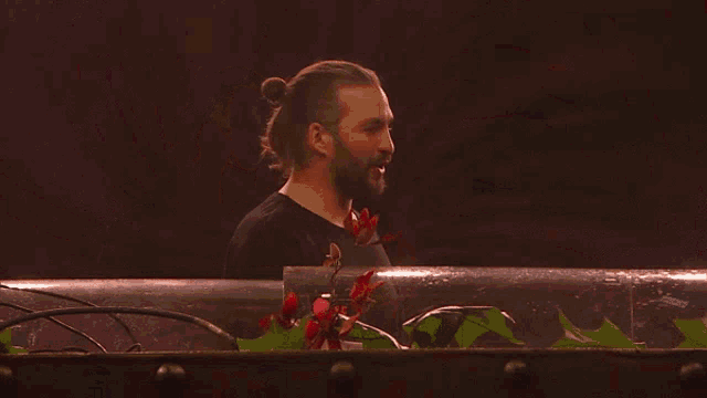 a man with a ponytail and a tattoo on his arm is giving the middle finger