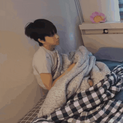 a person laying on a bed with a plaid blanket on it