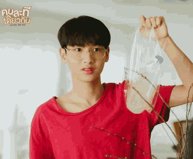 a man in a red shirt is holding a plastic bag with a bottle in it