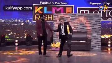 two men are dancing on a stage in front of a sign that says klm fashion partner