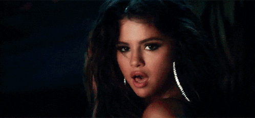 a woman in a black bra and earrings is looking over her shoulder .