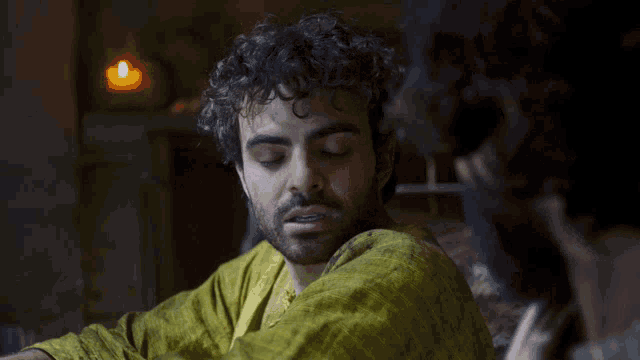 a man with curly hair and a beard looks to the side