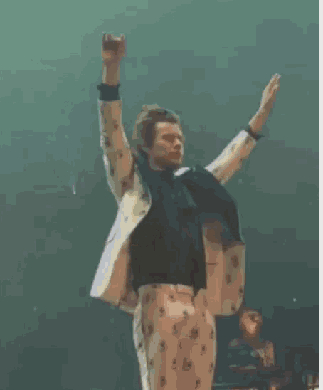 a man in a suit is making a peace sign with his hands in the air on a stage .