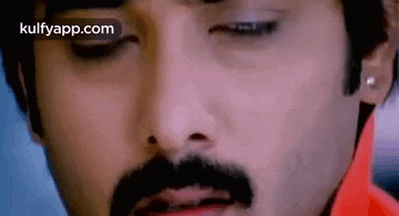 a close up of a man 's face with a mustache and earring .