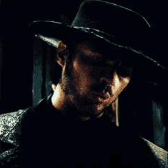 a man with a beard is wearing a black hat and looking at the camera .