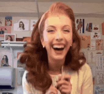 a woman with red hair is laughing while holding a glass of wine .