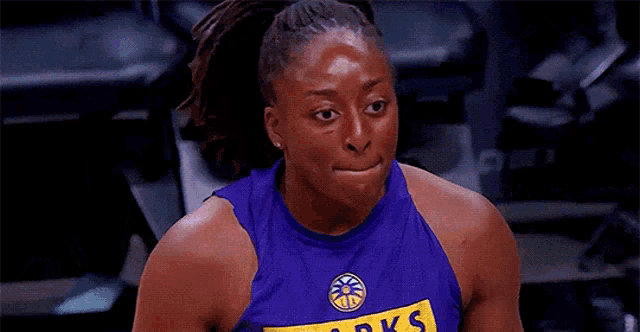 a female basketball player in a blue tank top is holding a basketball .