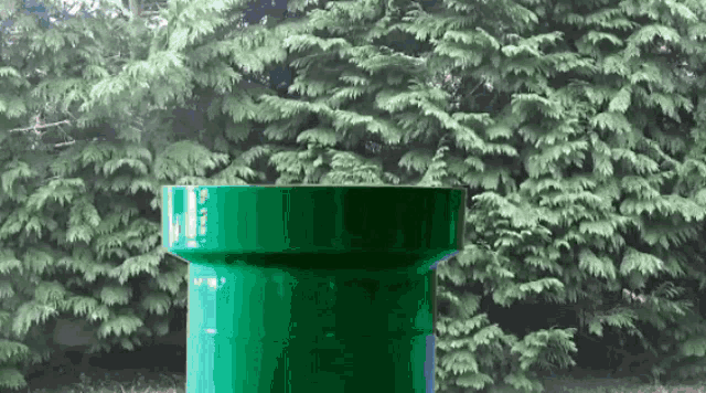 a green pipe with the number 7 on it in front of trees