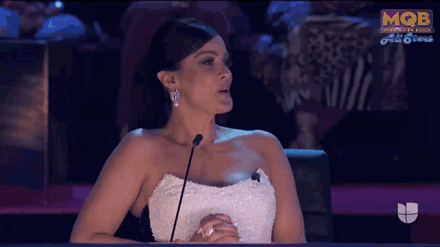 a woman in a white dress speaking into a microphone on a screen that says mob on it