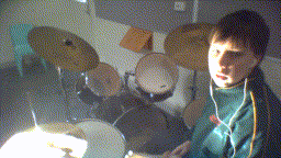 a man playing drums in a dark room with a drum set in the background