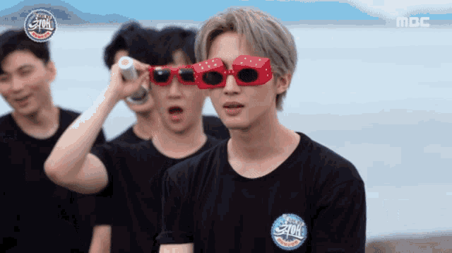 a group of young men wearing black shirts and red sunglasses with the word mbc on the bottom right