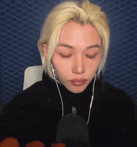 a man with blonde hair is wearing ear buds and looking down
