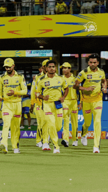 a group of cricket players wearing yellow uniforms are running on a field