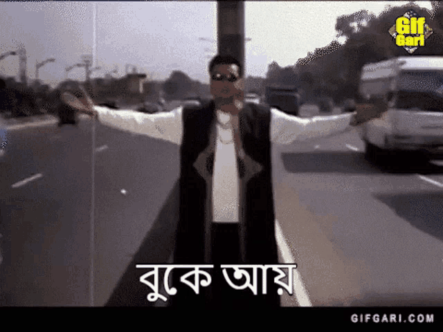 a man standing on the side of a road with his arms outstretched in front of a sign that says gif gari