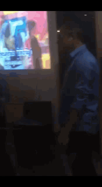 a blurry picture of a man standing in front of a television screen