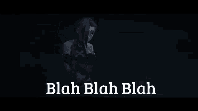 a woman with blue hair is standing in the dark with the words `` blah blah blah '' written on the bottom .