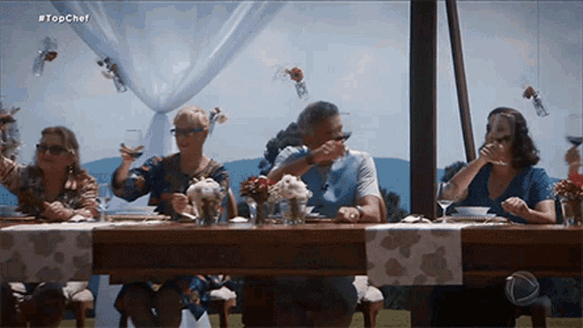 a group of people are sitting at a table with a sign that says topchef