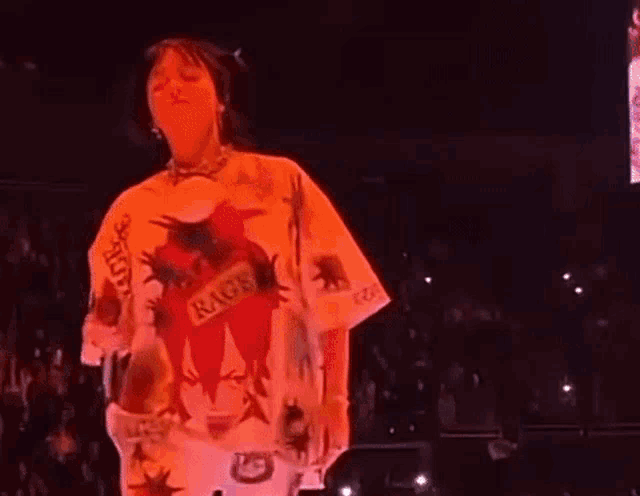 a woman is standing on a stage wearing a t-shirt with a picture of a person on it .