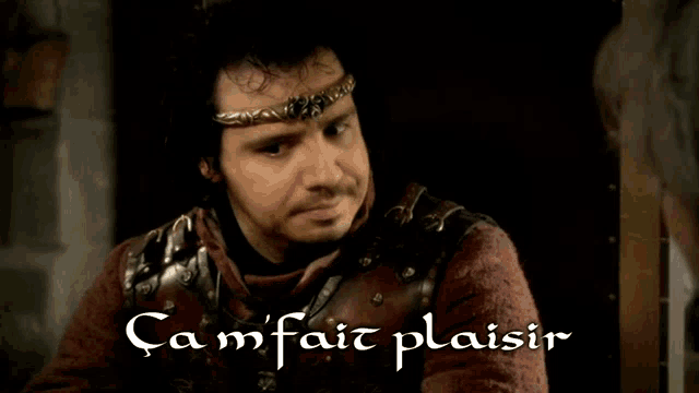 a man with a crown on his head is sitting in front of a sign that says cam fait plaisir