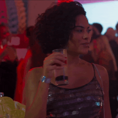 a woman is holding a glass of water in a crowded room