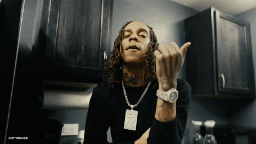 a man with dreadlocks wearing a watch and a necklace with the number 75 on it