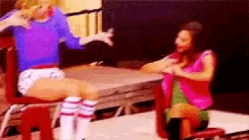 two women are sitting on chairs and talking to each other .