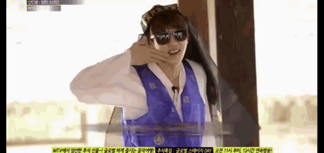 a man wearing sunglasses and a blue vest stands in front of a screen that says mtv on it