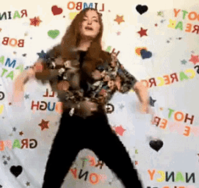 a woman is dancing in front of a colorful backdrop that says ' yto ' on it